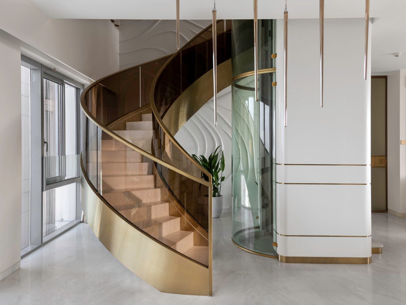 The brass spiral staircase and glass capsule lift at A Still Summit
